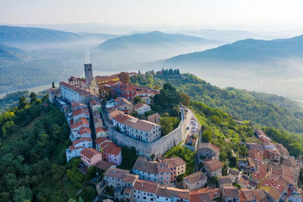 Antica città di Montona in cima alla montagna. La città è circondata da un muro di fortezza. L'immagine di sfondo sono le montagne e la nebbia ai piedi delle montagne. Istria, Croazia. La vista dal drone.
