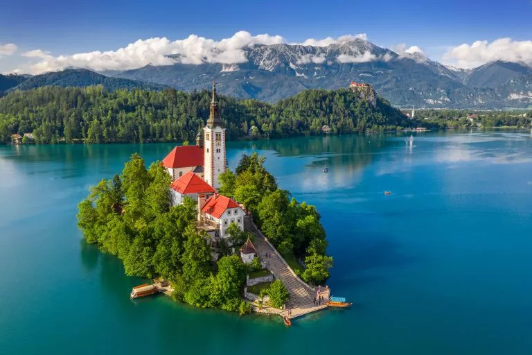 Bled, Slovenië - Luchtfoto van het prachtige meer van Bled (Blejsko Jezero) met de bedevaartskerk Maria Hemelvaart op een klein eilandje en het kasteel van Bled en de Julische Alpen op de achtergrond in de zomer