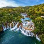Krka, Croazia - Vista aerea delle bellissime cascate di Krka nel Parco Nazionale di Krka in una luminosa mattina d'estate con fogliame verde, acqua turchese e cielo azzurro