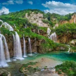 Plitvice, Croazia - Le bellissime cascate dei laghi di Plitvice (Plitvička jezera) nel Parco Nazionale di Plitvice in una luminosa giornata estiva con cielo azzurro e nuvole, fogliame verde e acqua turchese