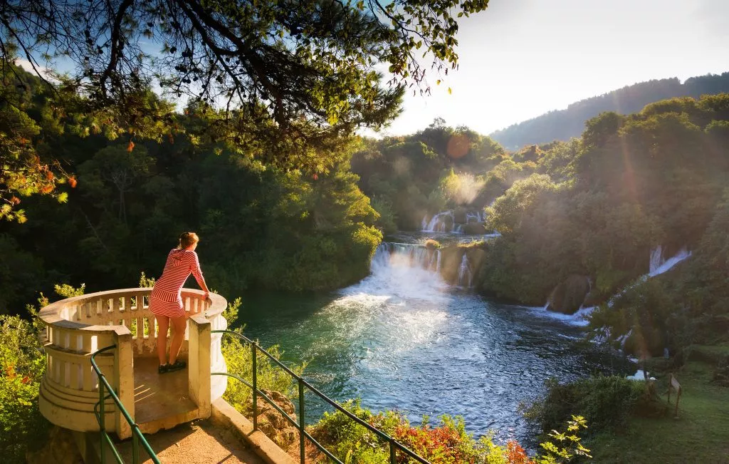 Junge Frau blickt auf die Wasserfälle des Flusses Krka im Krka-Nationalpark in Kroatien